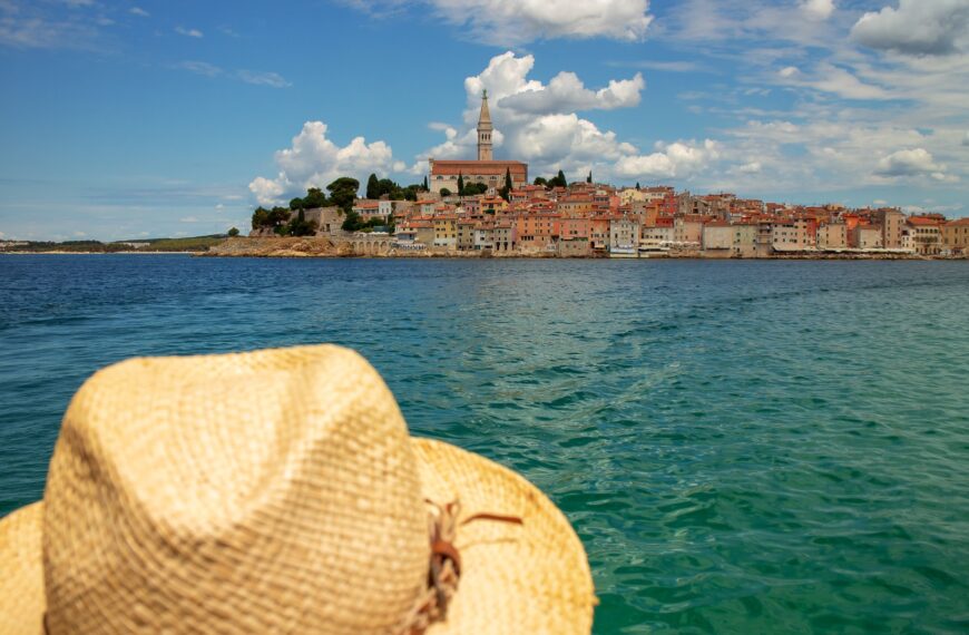 This image shows a straw hat in the foreground and Rovinj in the background.